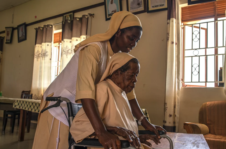 A Sister assisting an elderly Sister seated in a wheelchair