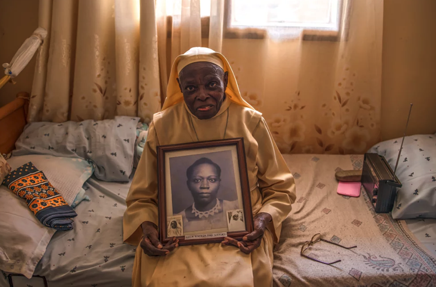 An elderly Sister holding a portrait from her youth